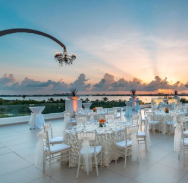 Guests can celebrate in style at a sophisticated seaside reception under the sunset sky.