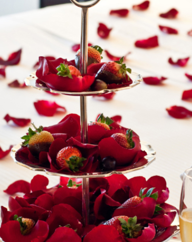 Fresh strawberries and rose petals create a romantic display on a beautifully arranged dessert stand.