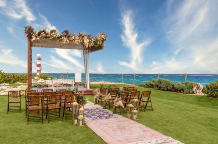 A charming beachfront wedding setup with rustic wooden chairs and a floral arch overlooking the ocean.