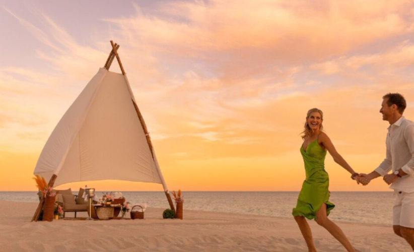 A couple runs hand in hand along the beach at sunset, embracing the joy of love and adventure.