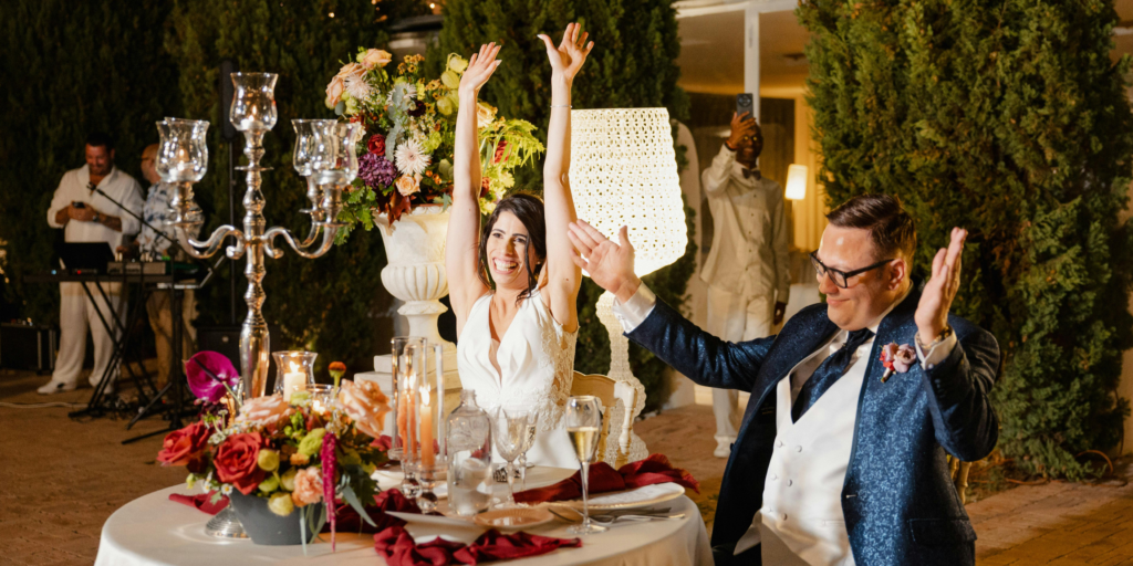 Bride and groom celebrating at wedding reception dinner table with candles and floral decor
