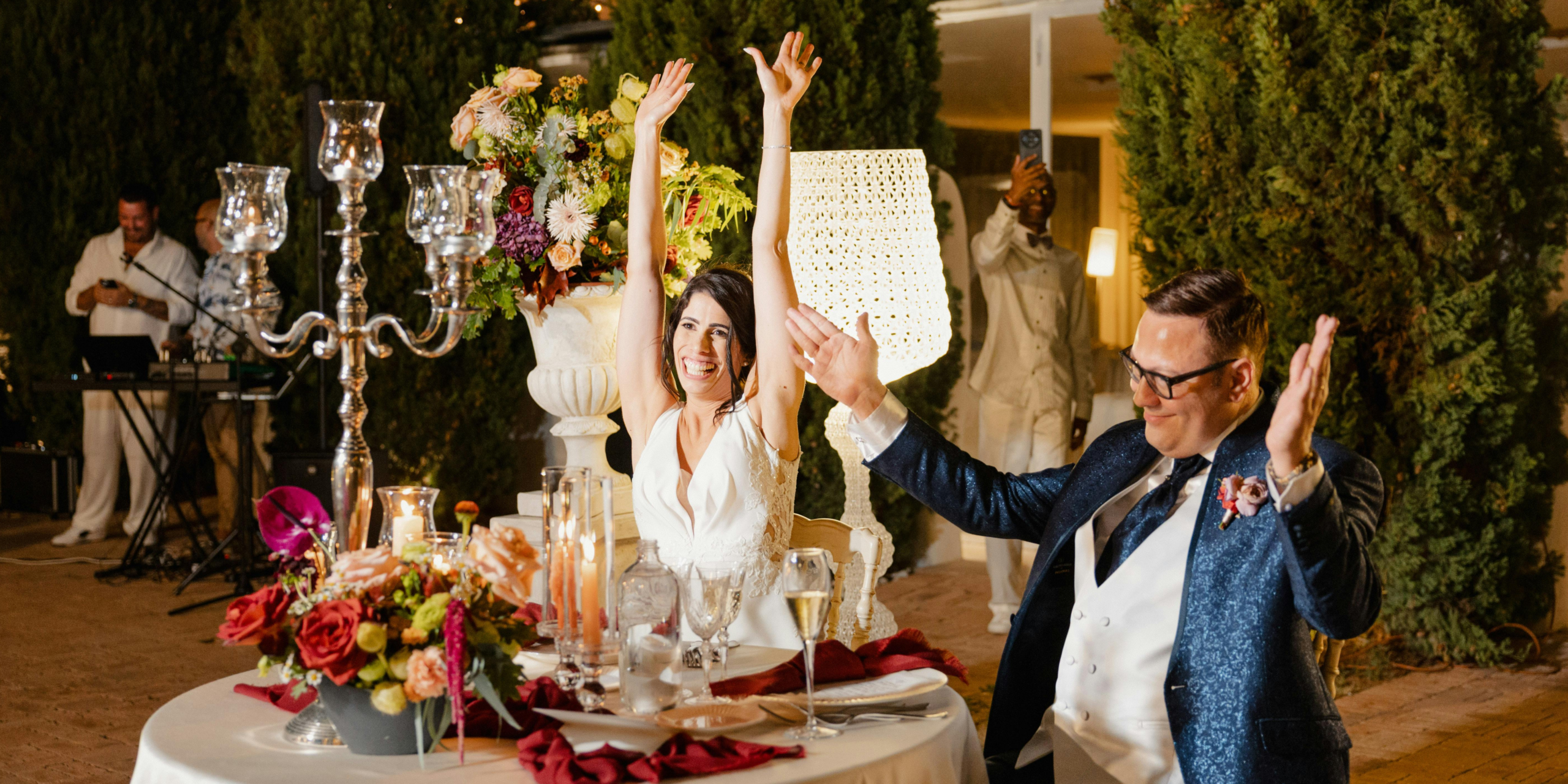 Bride and groom celebrating at wedding reception dinner table with candles and floral decor