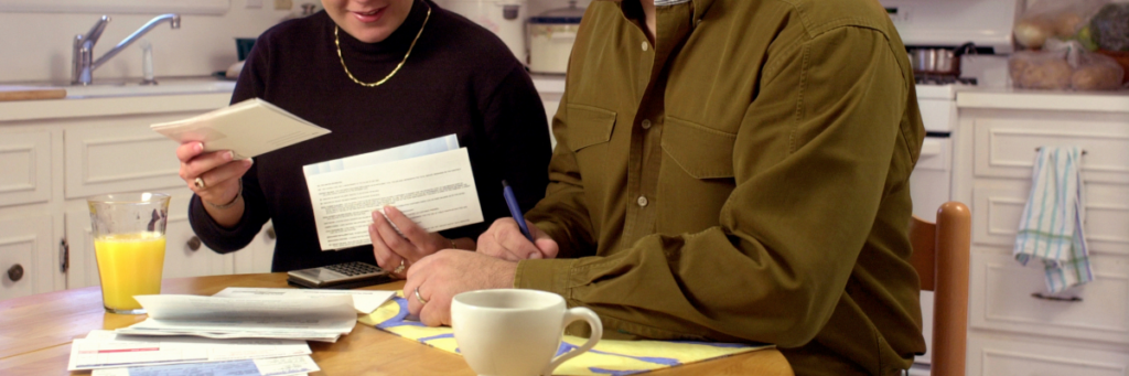 Newlywed couple reviewing legal and financial documents together at a kitchen table