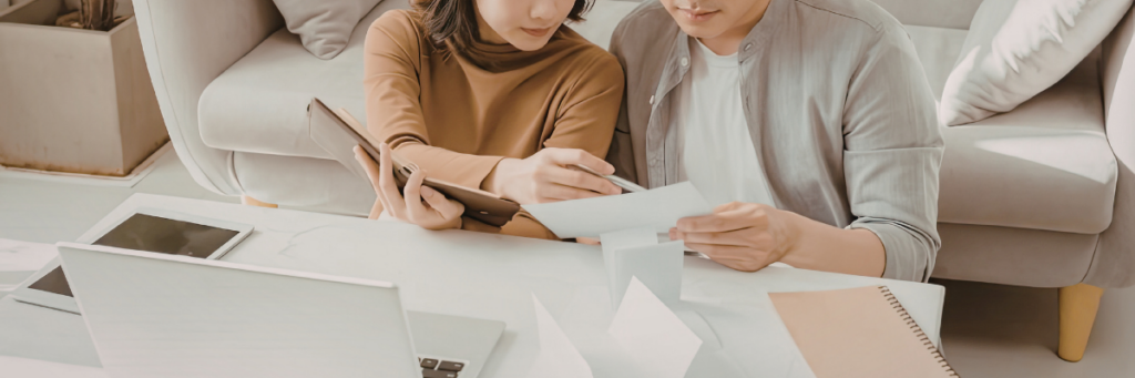 Couple reviewing paperwork and planning post-wedding financial updates at home