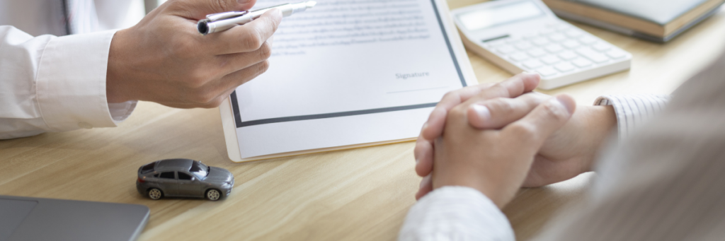 A couple sits across from a professional while reviewing a legal document.