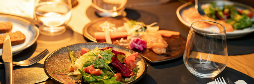 Elegant plated meal at an intimate wedding reception, featuring a fresh salad, carefully arranged dishes, and warm candlelight.